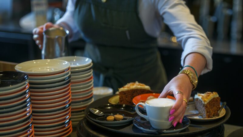 Una mesera atiende la mesa de un restaurante, decorada con platos y copas para los comensales