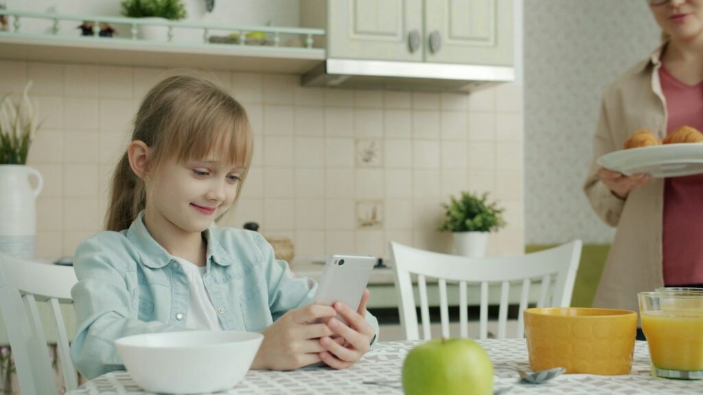 Niño usando un teléfono inteligente en casa, en una escena relacionada con los hábitos digitales durante la infancia