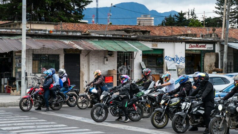 Manifestantes marchando por una calle mientras agentes de seguridad vigilan la movilización