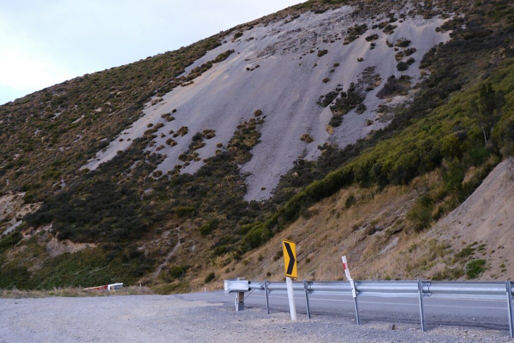 Material de tierra y rocas bloqueando parcialmente una carretera durante la temporada de lluvias