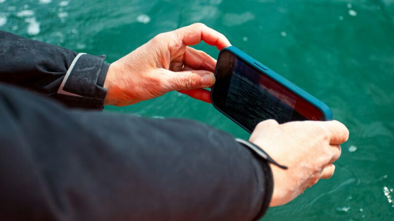 Teléfono inteligente moderno junto a elementos relacionados con carga y resistencia al agua