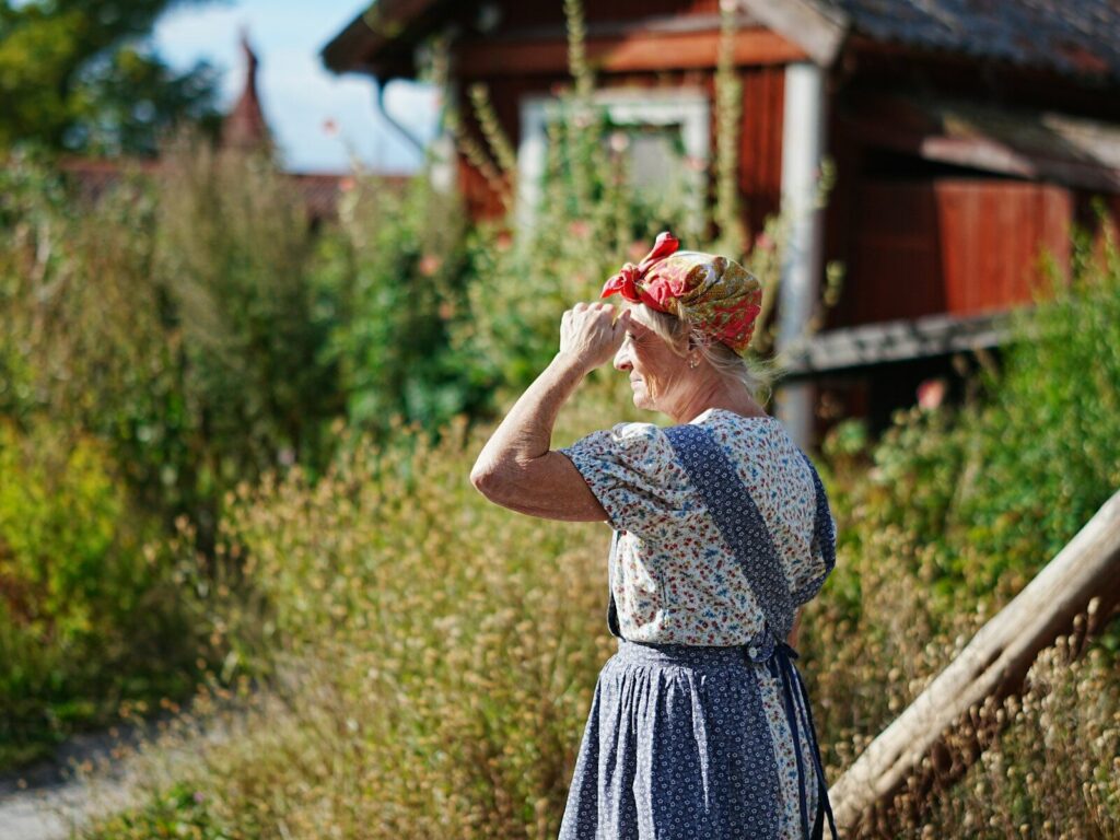 Escena de una película de época con dos mujeres en un paisaje rural y una cabaña