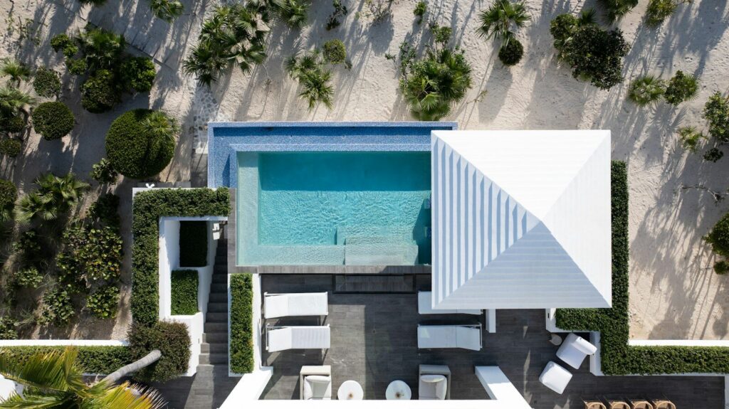 Villa de lujo con piscina y acceso directo a una playa de arena blanca en una isla del Caribe.